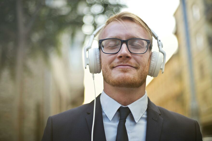 Man in suit with headphones enjoying a music mood boost with eyes closed
