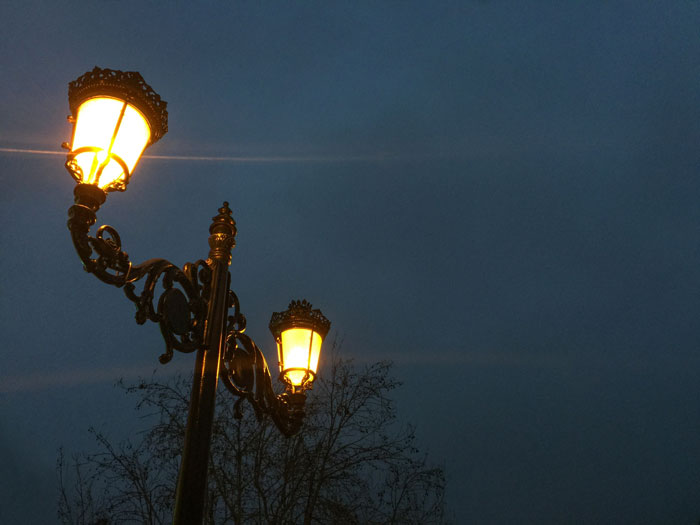 Ornate street lamps glowing at night with dark sky