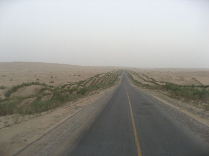 Desert road stretching into the horizon in a barren sandy landscape