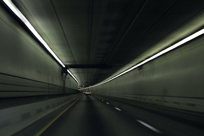 Vehicles driving through dark highway tunnel, a risky road environment for truckers