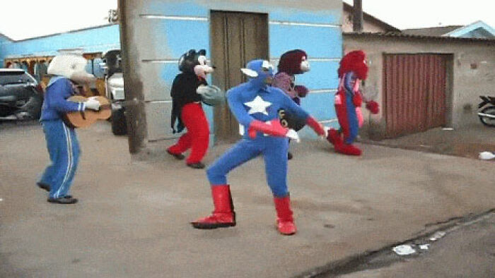Group of people dancing outdoors in unusual superhero and cartoon costumes