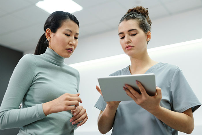 Two women discussing something on a tablet, representing an insular religious community discussion