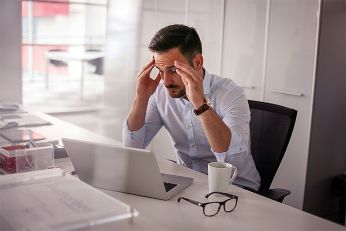 Stressed businessman working on laptop, reflecting on losing millions after rude dinner behavior Stressed businessman working on laptop, reflecting on losing millions after rude dinner behavior