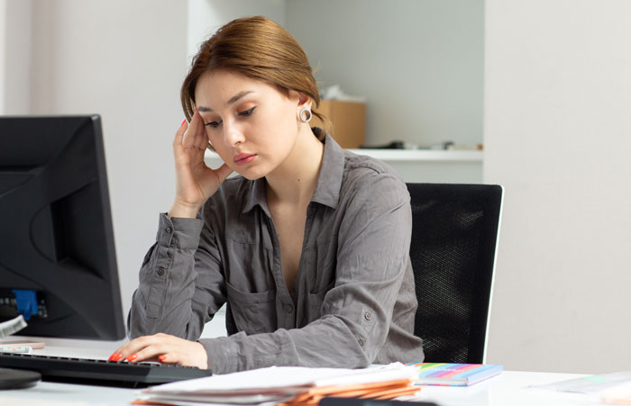 Woman thinking at computer about AI usage and work challenges