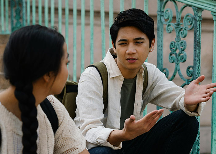 Two young people talking; the man gestures expressively. Illustrates behaviors common in people of low intelligence.