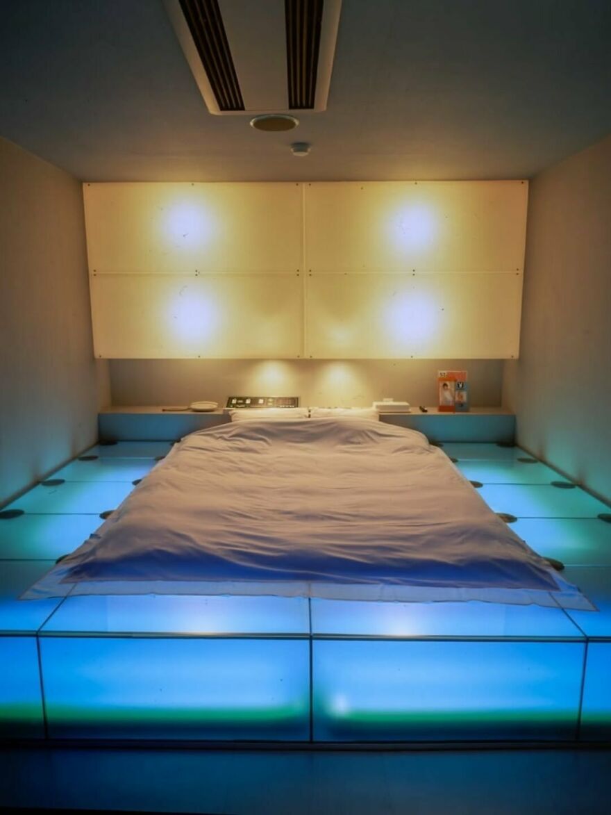 A futuristic Japanese hotel room with a bed on a glowing blue platform, showcasing unique Japanese things.