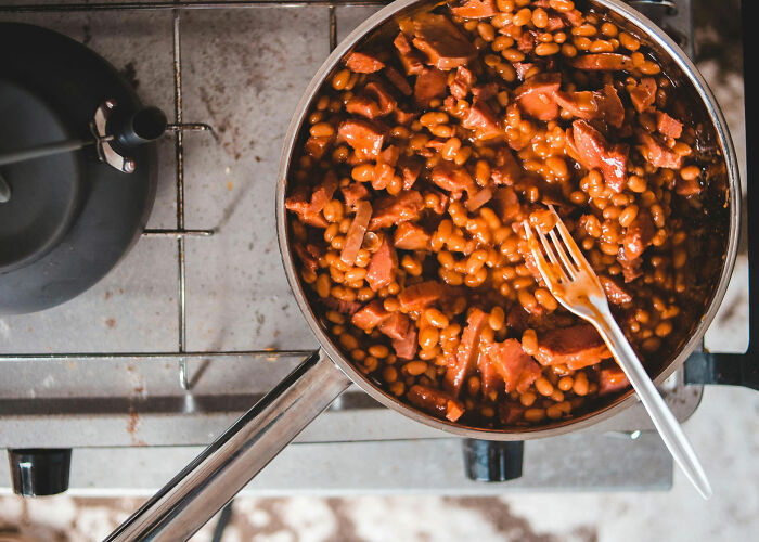 A pot of baked beans with meat on a stove, symbolizing budget-friendly meals when people worry about the economy and their wallets.