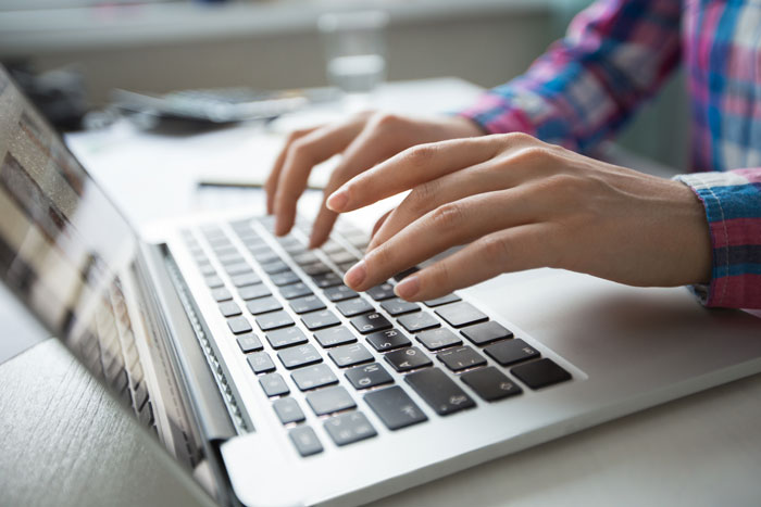 Person typing on a laptop, researching facts to avoid repeating wrong information on Reddit.