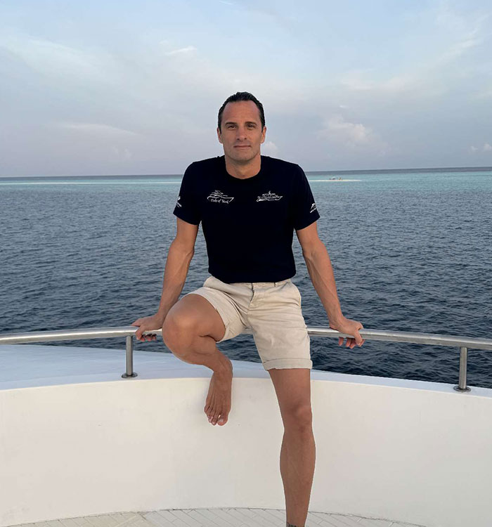 Man posing on boat railing with ocean background in Maldives diving trip