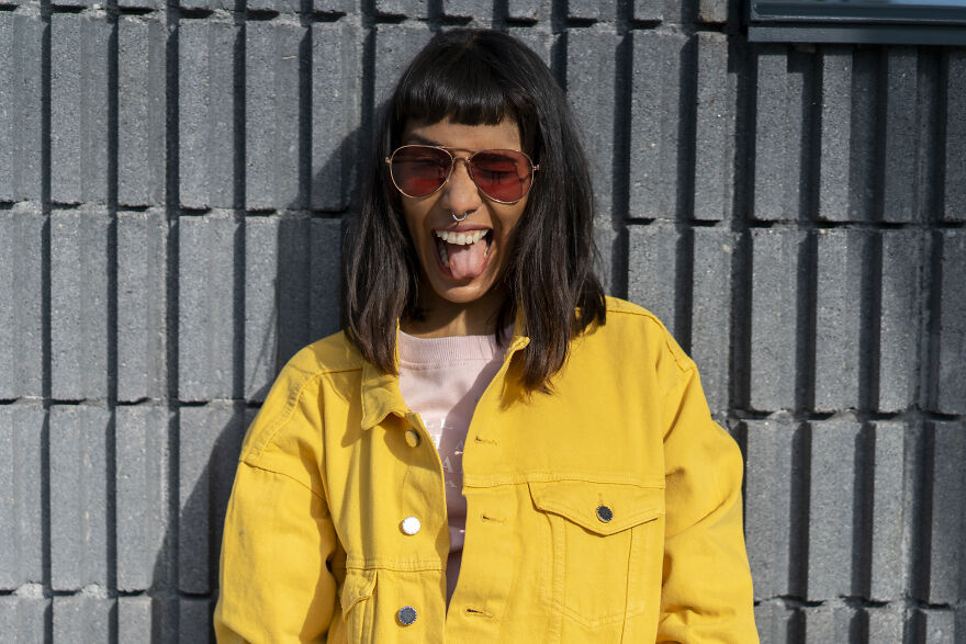 Woman in yellow jacket showing playful mood booster expression outdoors