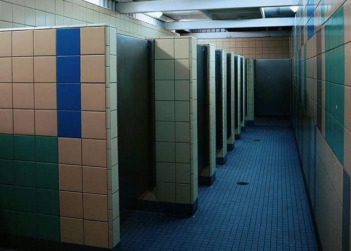 Empty public restroom stalls with tiled walls and floors.