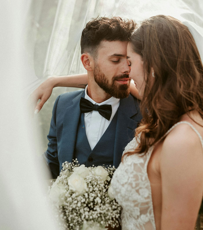 Close up of bride and groom embracing under wedding veil