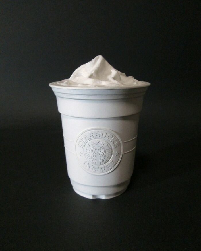Paper Starbucks cup with whipped cream on black background