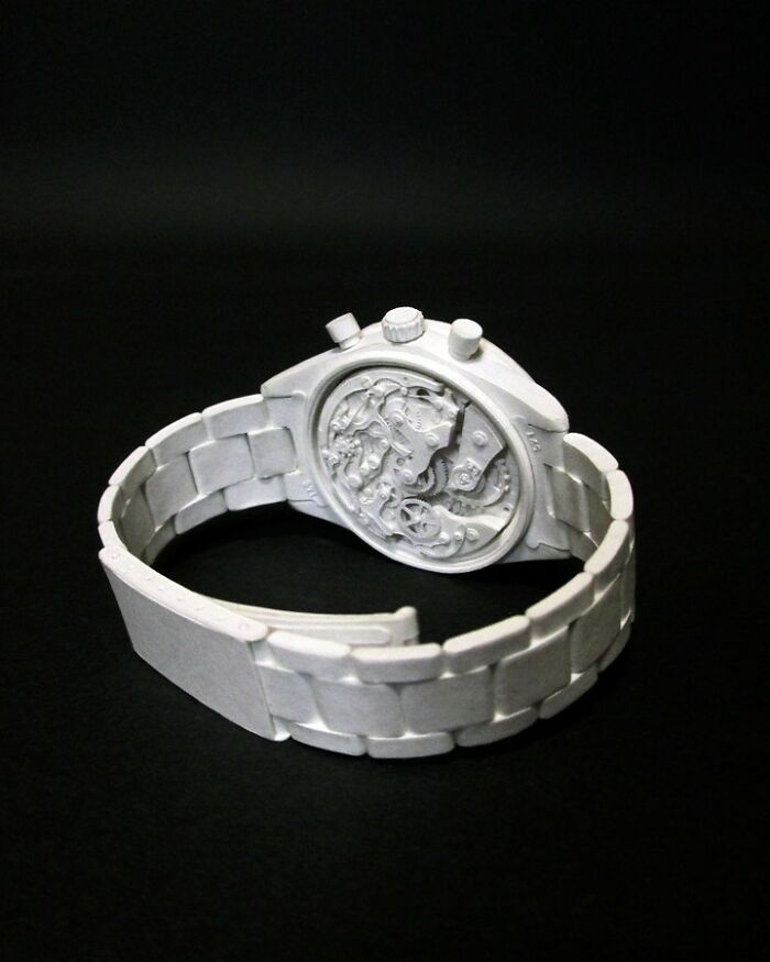 Detailed paper watch with visible gears and circuitry on black background