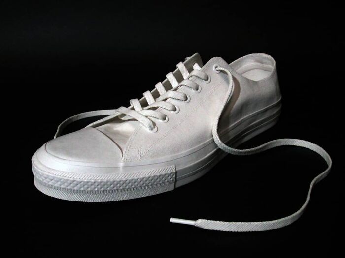 White paper sneaker with visible shoelaces on dark background