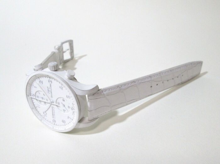 White paper watch with leather strap on white surface