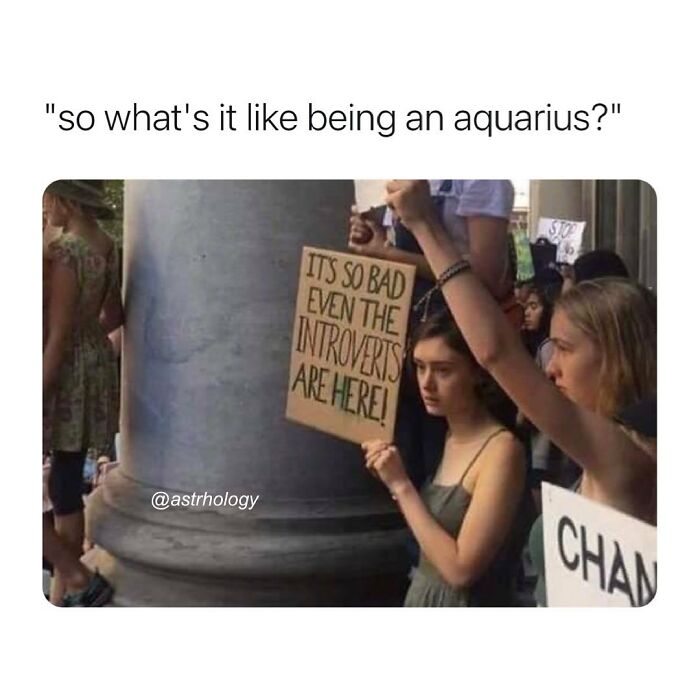 A woman holds a sign saying "IT'S SO BAD EVEN THE INTROVERTS ARE HERE!" Relatable and funny astrology memes.