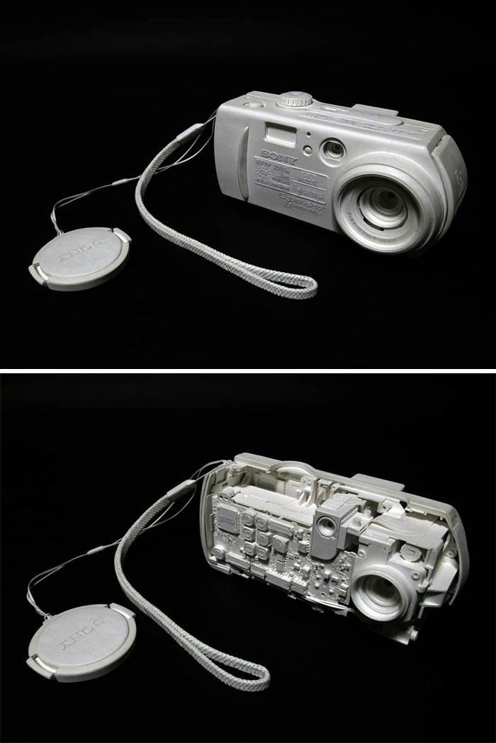 Paper digital camera replica with attached lens cap and visible buttons