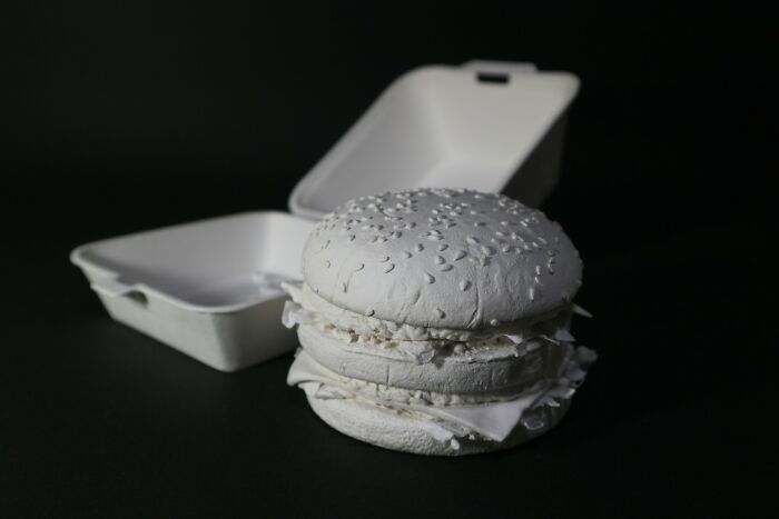 Paper hamburger with bun and filling in a takeout container