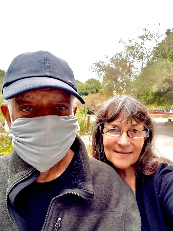 Elderly couple outdoors with man wearing mask and woman smiling comforting moment