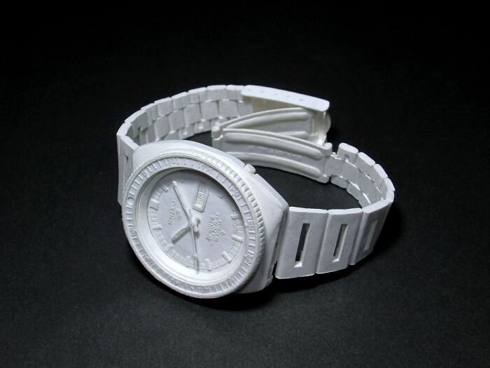 Paper wristwatch with detailed face and adjustable strap on black background