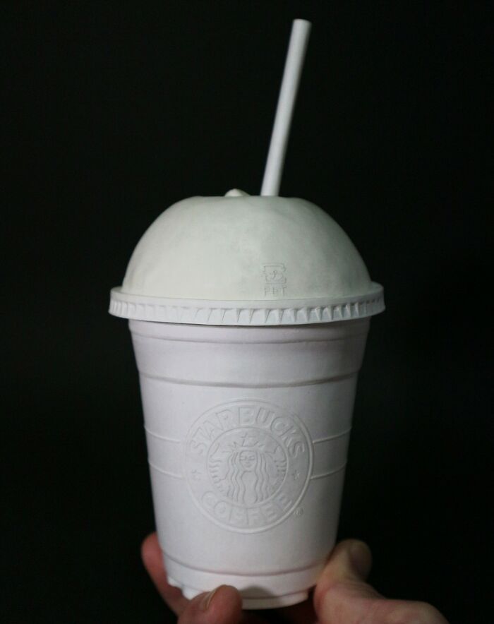 Hand holding detailed paper Starbucks coffee cup with straw