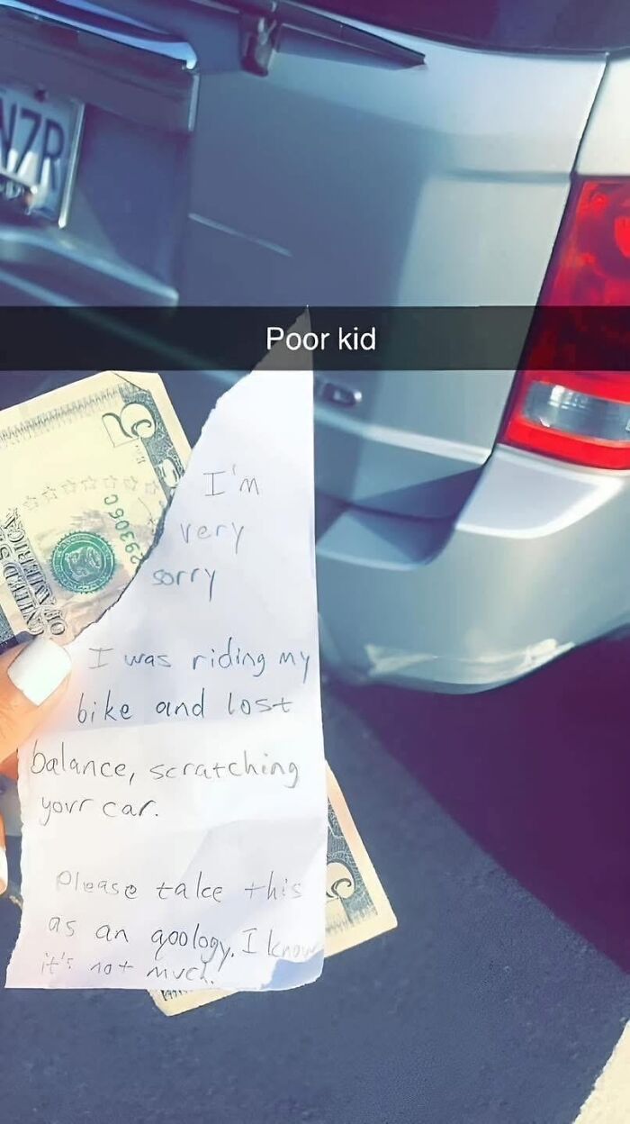 Hand holding apology note and money for scratching car showing wholesome kindness