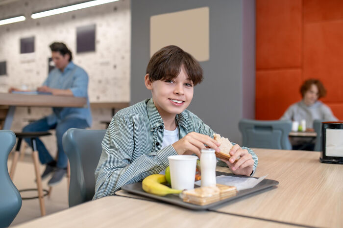 A smiling boy at a table with a meal, evoking thoughts of second-hand embarrassment when witnessing others' cringe moments.
