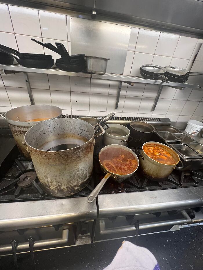 Large pots with sauces cooking on a commercial kitchen stove