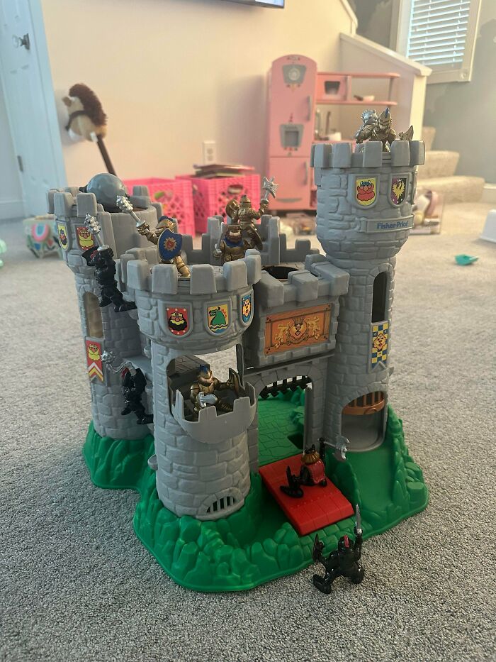 A Fisher-Price toy castle surrounded by small knight figures, a nostalgic image representing a throwback for 90s kids.