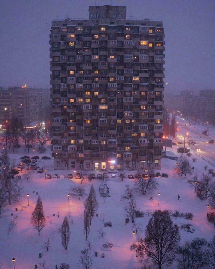Eerie urban hell high-rise apartment building glowing at night in snowy cityscape