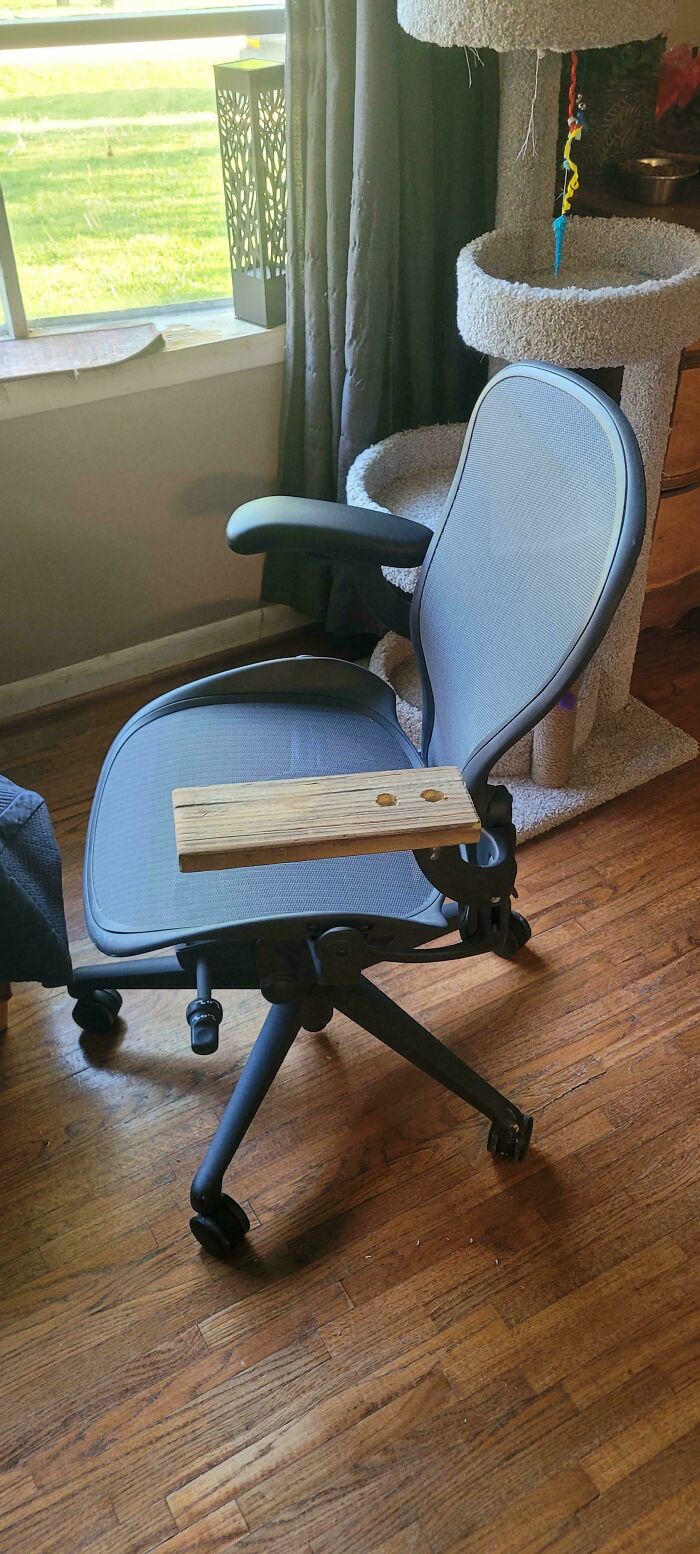 An office chair with a wooden plank attached as an armrest, a clever solution from random junk.
