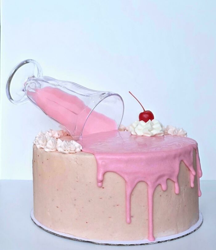 Creative cake with pink drip frosting and glass tilted on top dessert