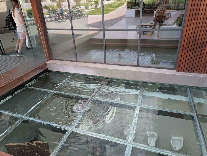 Bathroom floor made of glass panels revealing urinals beneath