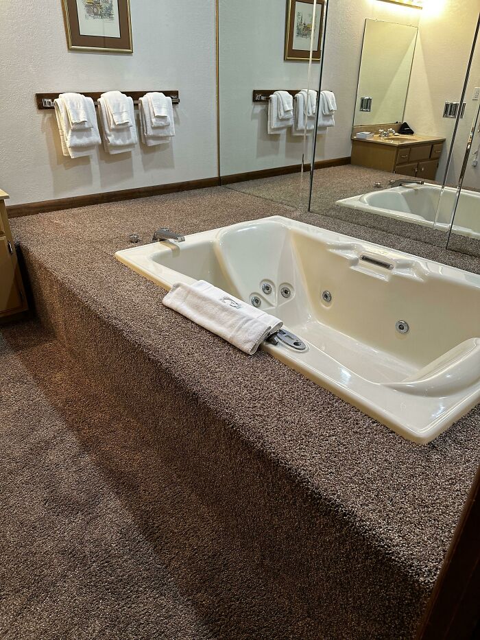Carpeted bathroom area surrounding a jacuzzi tub in an unusual bathroom design