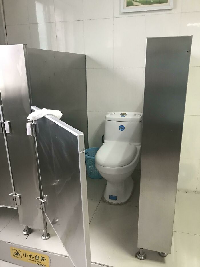 Public restroom with obstructed toilet stall door and poor partition design