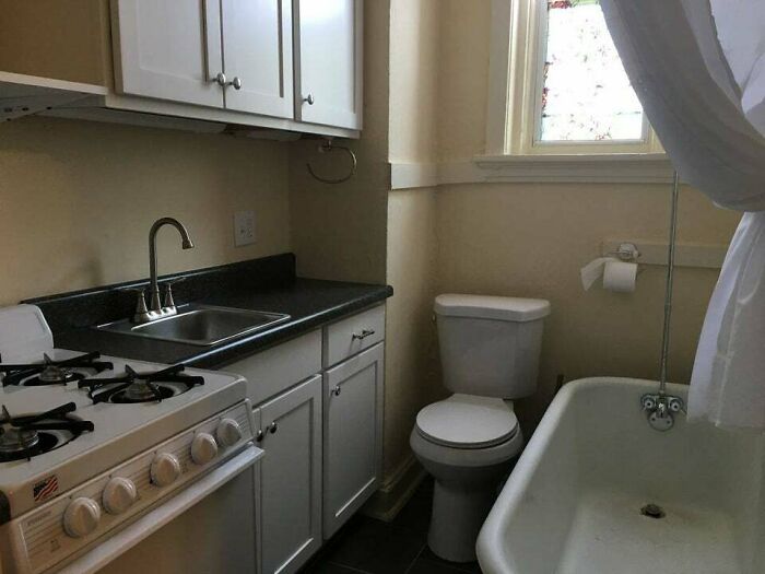 Questionably designed bathroom with toilet next to kitchen stove and sink