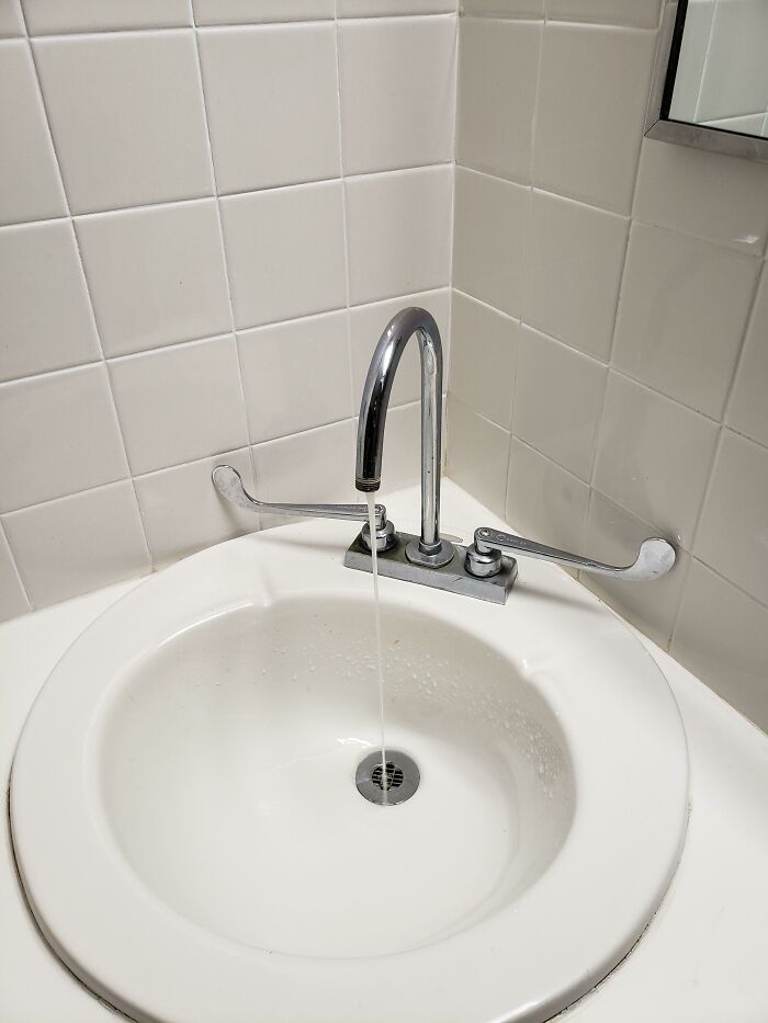 Sink with faucet and handles awkwardly spaced in small bathroom