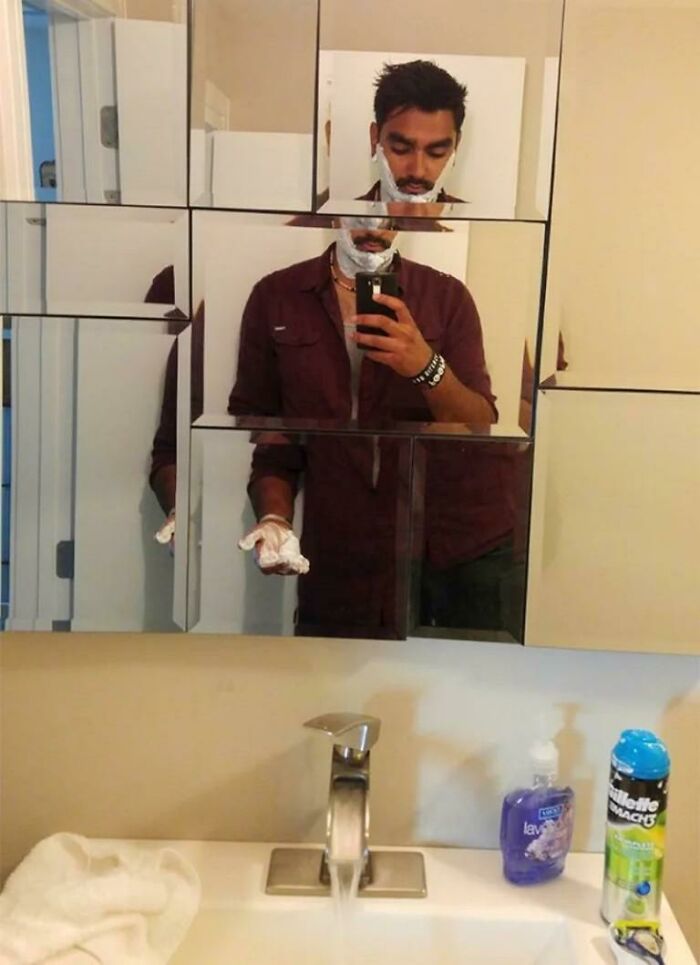 Man with distorted face reflected in oddly segmented bathroom mirrors