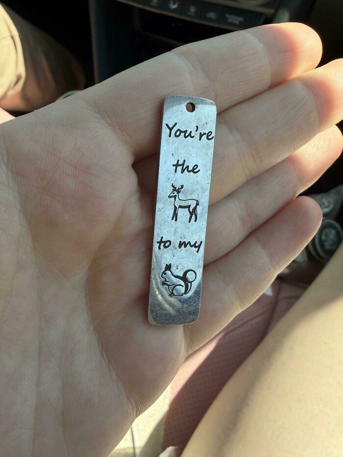 A person holds a metal tag that reads "You're the deer to my squirrel". An interesting meaning.