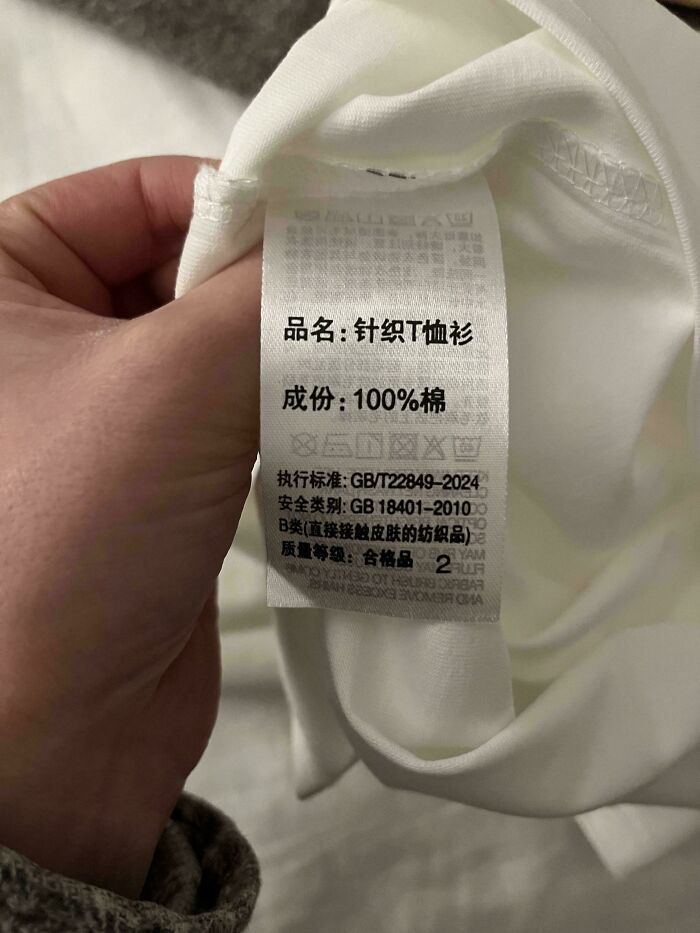 A hand holds up a clothing label with Chinese text and care symbols. This textile information could be something interesting.