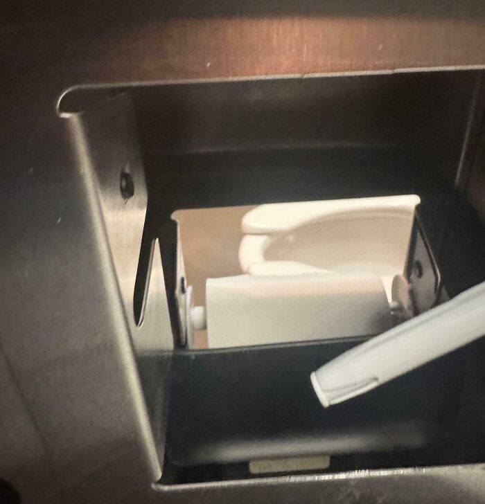 Toilet paper dispenser with a clear view of toilet accidentally visible through cutout