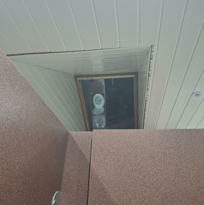 Toilet bowl visibly placed behind a ceiling skylight creating privacy issues in bathroom