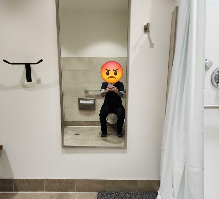 Toilet reflected in a full-length mirror showing poor bathroom layout with an angry emoji
