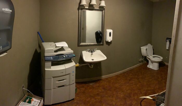 Unusual bathroom with printer next to sink and toilet on brown floor