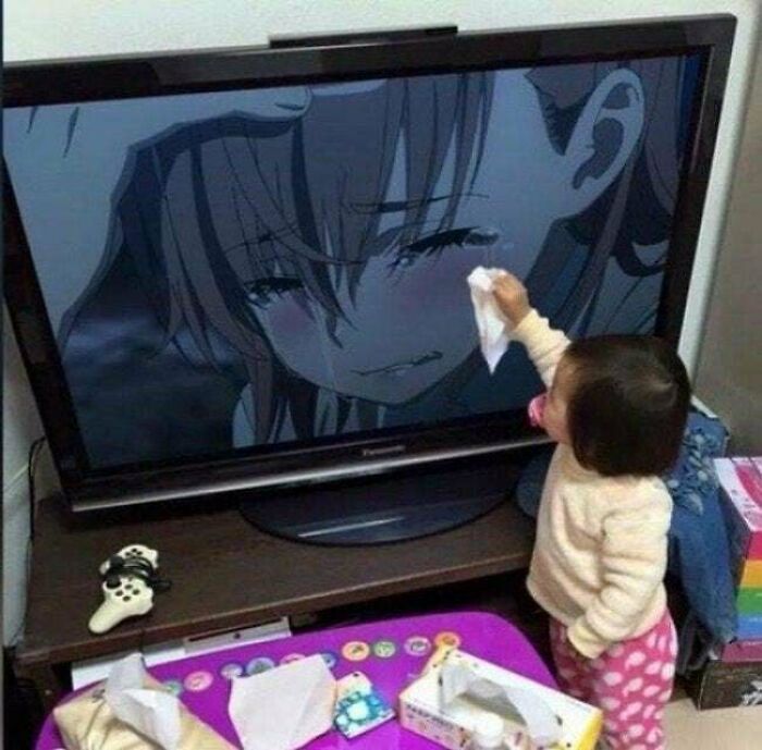 A wholesome pic of a toddler wiping tears from a crying anime character on a TV screen, embodying wholesome pics.
