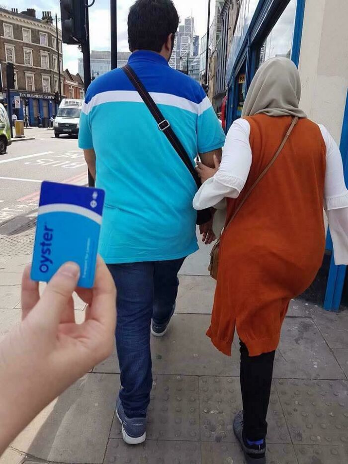 Hand holds an Oyster card matching a man's blue shirt, an accidental color match on a street. Cortisol levels.