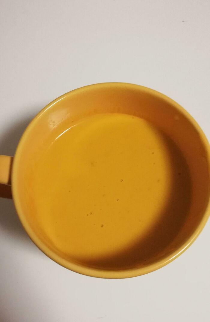 A close-up aerial view of a vibrant orange mug filled with orange liquid, an accidental color match that may lower cortisol levels.