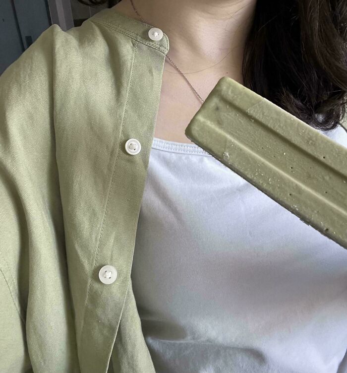 A woman's green linen shirt matches a green bar, a satisfying accidental color match that may lower cortisol.