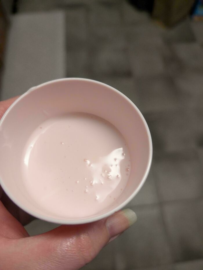A hand holding a pink cup filled with a pale pink liquid, illustrating an accidental color match that may lower your cortisol levels.
